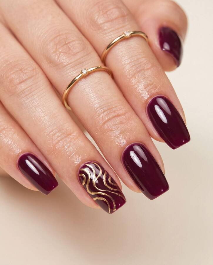 Square oval nails in plum with a gold chrome swirl